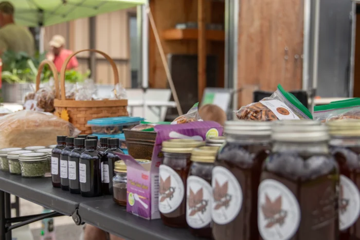 Farmers market stall with jars of extracts, preserves and packaged nuts displayed on shelves