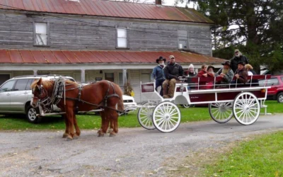 Horse-drawn wagon with passengers in front of old wooden building