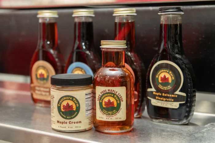 Glass jars of 100 percent pure maple syrup from Frostmore Farm, including regular maple syrup, maple cream and maple balsamic vinaigrette in view.
