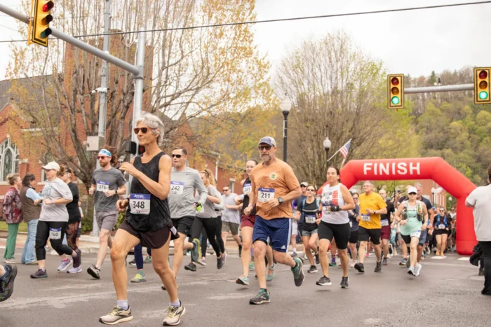 A group of runners starting the race. Behind the group is a red inflatable arch with "Finish" written in white at the top. 