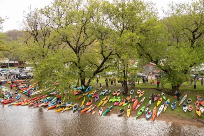An aerial shot of colorful kayaks and canoes lining the riverbank before the race.