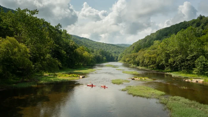 Two people slowly float down the Greenbrier River in kayaks.