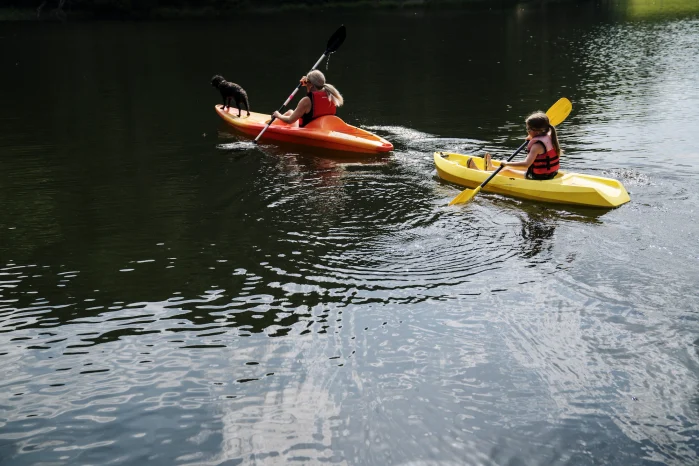 A mother and daughter kayaking around Watoga State Park. There is a small black dog on the mother's kayak. 